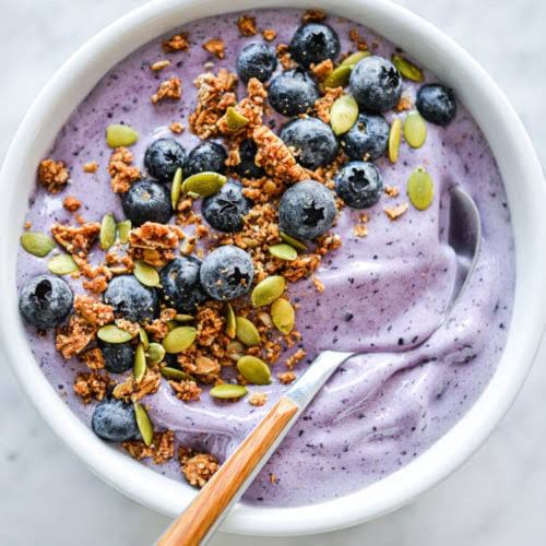 Blueberry smoothie bowl topped with granola and pumpkin seeds