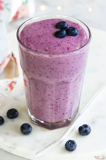 A glass of creamy blueberry smoothie with fresh blueberries